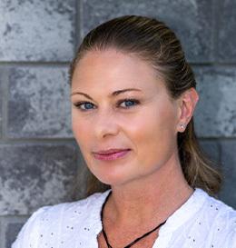 Woman with a neutral expression against a gray stone wall