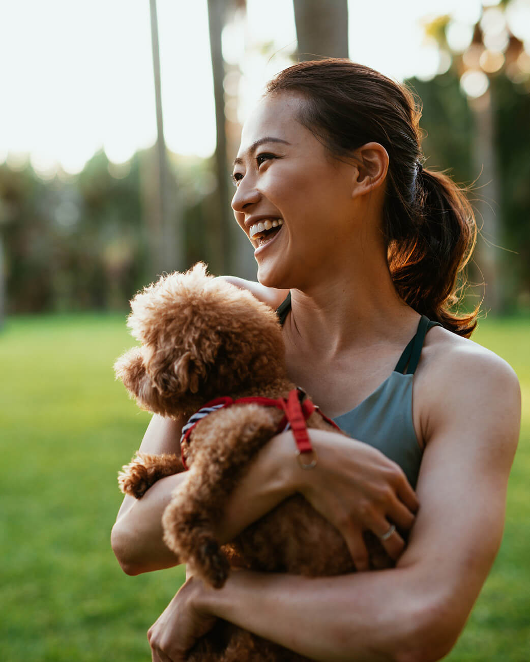 Woman holding a small brown dog in a park