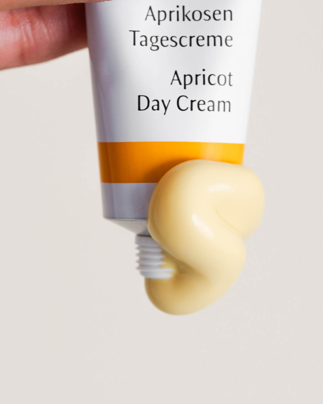 Tube of Apricot Day Cream with a visible amount of cream on a light background.