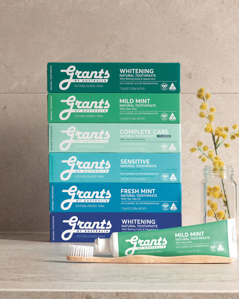 Stack of Grants toothpaste boxes on a wooden surface with a neutral background.