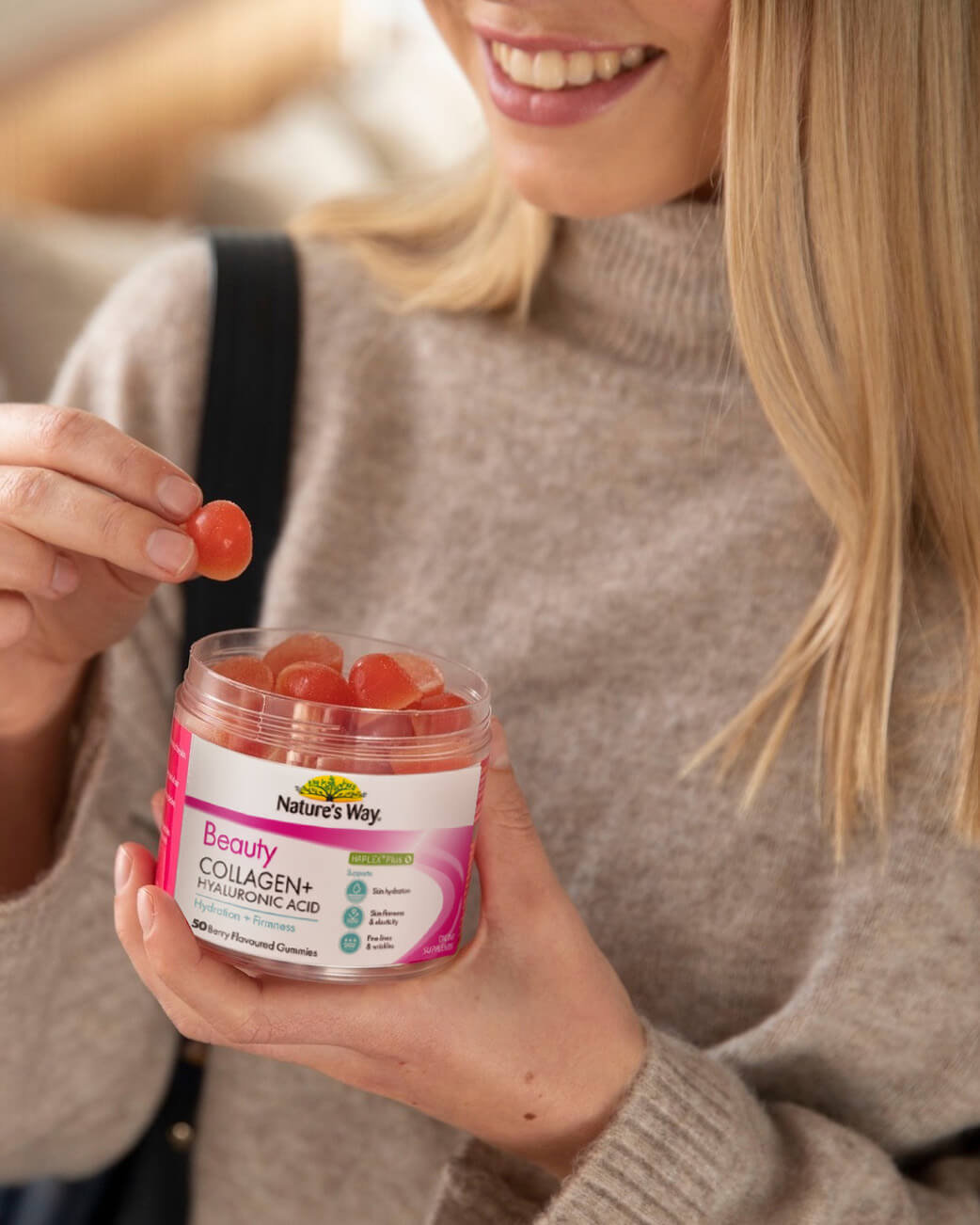 Woman holding a container of Nature's Way Beauty Collagen+ gummy supplement.