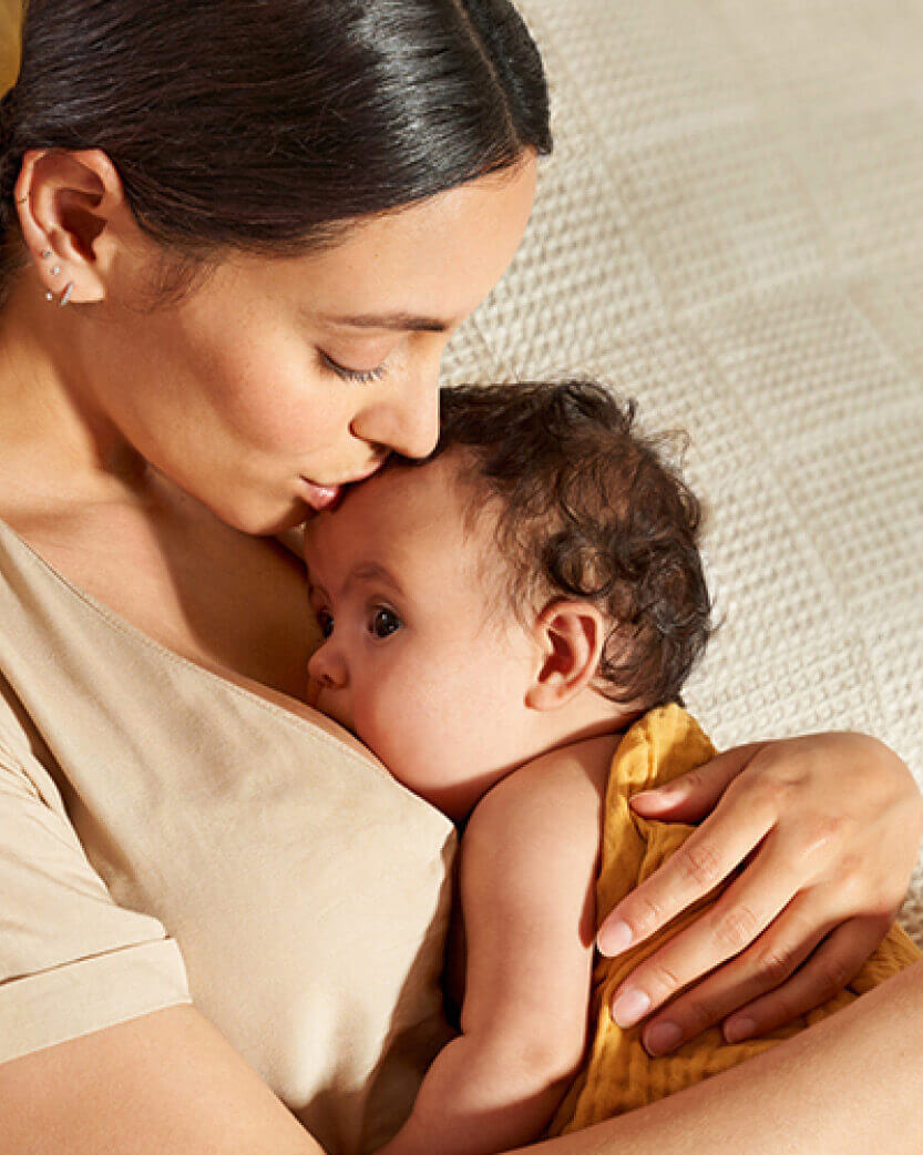 Woman holding a baby close, with a soft, neutral background.