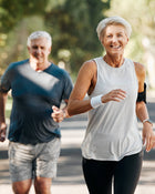 Two elderly individuals jogging outdoors on a sunny day.