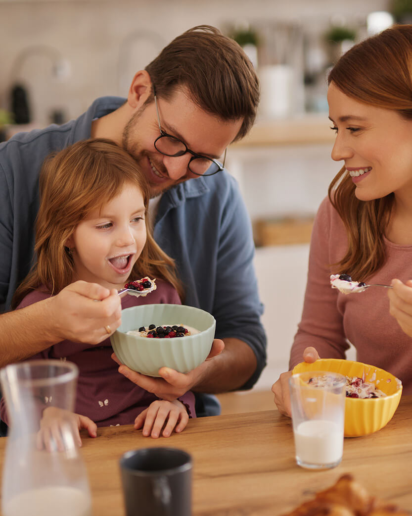 Family of three enjoying a meal together at a table.
