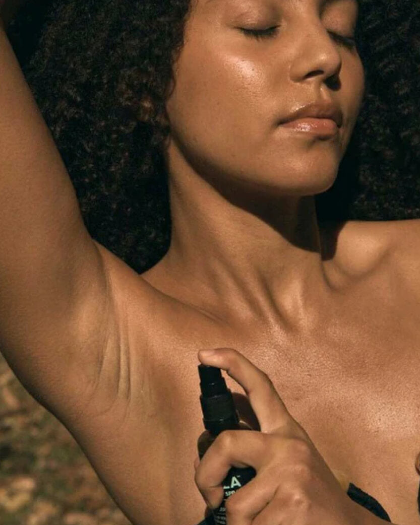 Person applying a spray product to their arm.