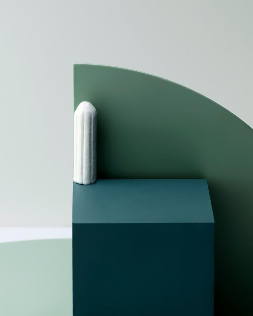 Green & blue geometric wall art with a white cylindrical object on a light gray background.