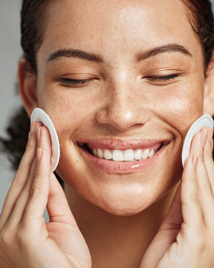 Woman cleaning her face with a white cloth, close-up shot.