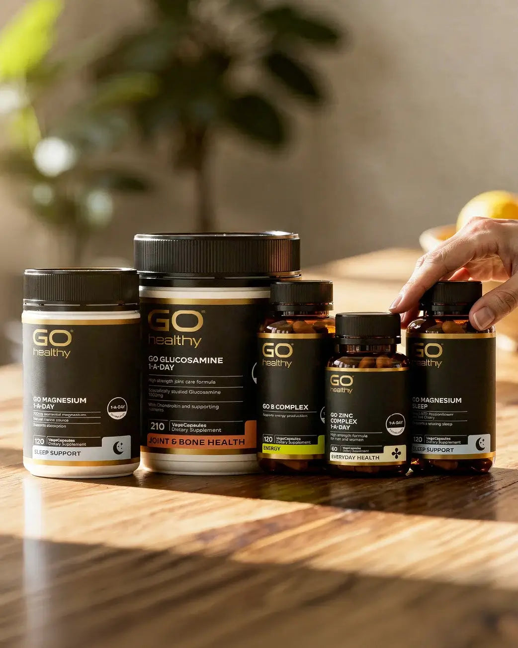 Collection of GO Healthy supplement jars on a wooden surface with a blurred background.