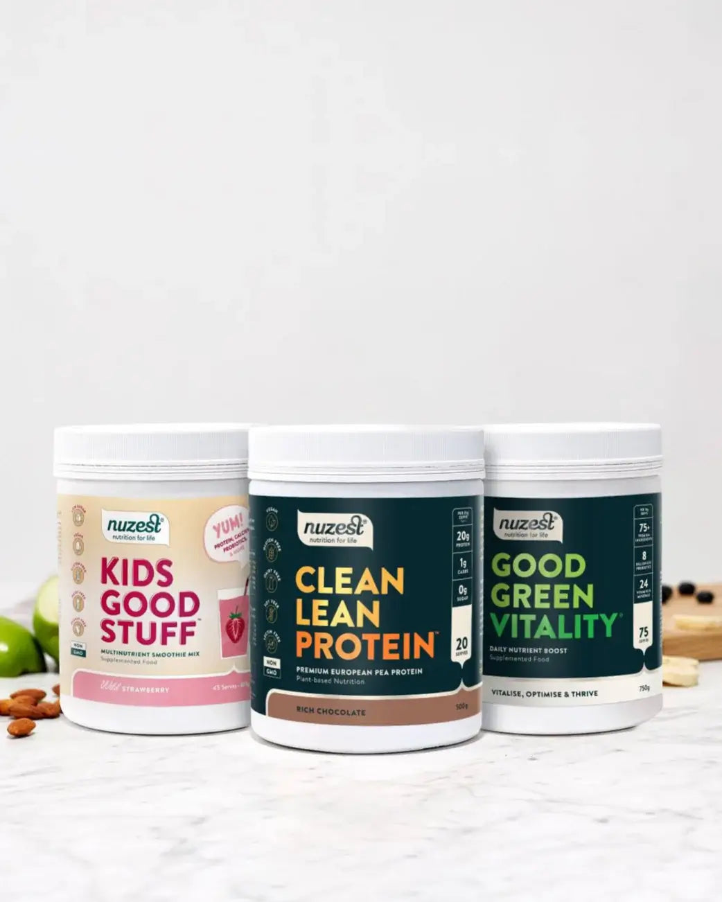 Three Nuzest protein powder containers on a white surface with a light gray background.