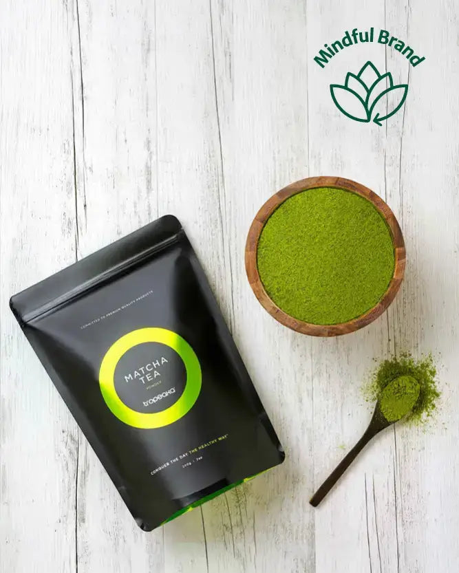 Matcha tea packaging and bowl with green powder on a wooden surface, featuring the Mindful Brand logo.