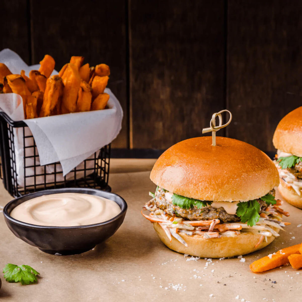 Burger with fries and sauce on a rustic surface.