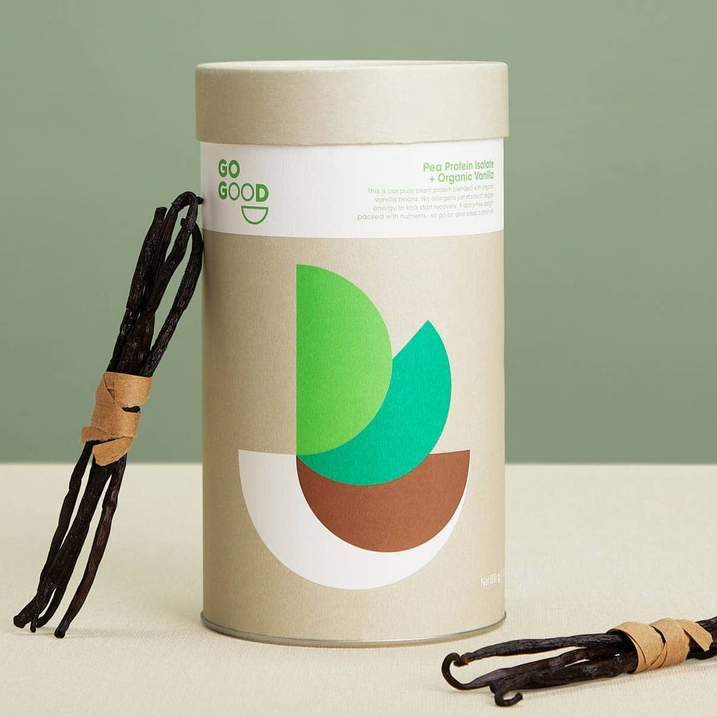 Vanilla beans next to a cylindrical container with green and brown design on a light background.