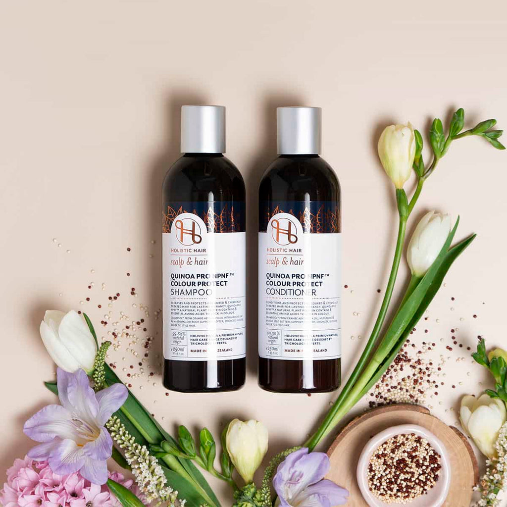 Two bottles of hair care products with flowers on a beige background