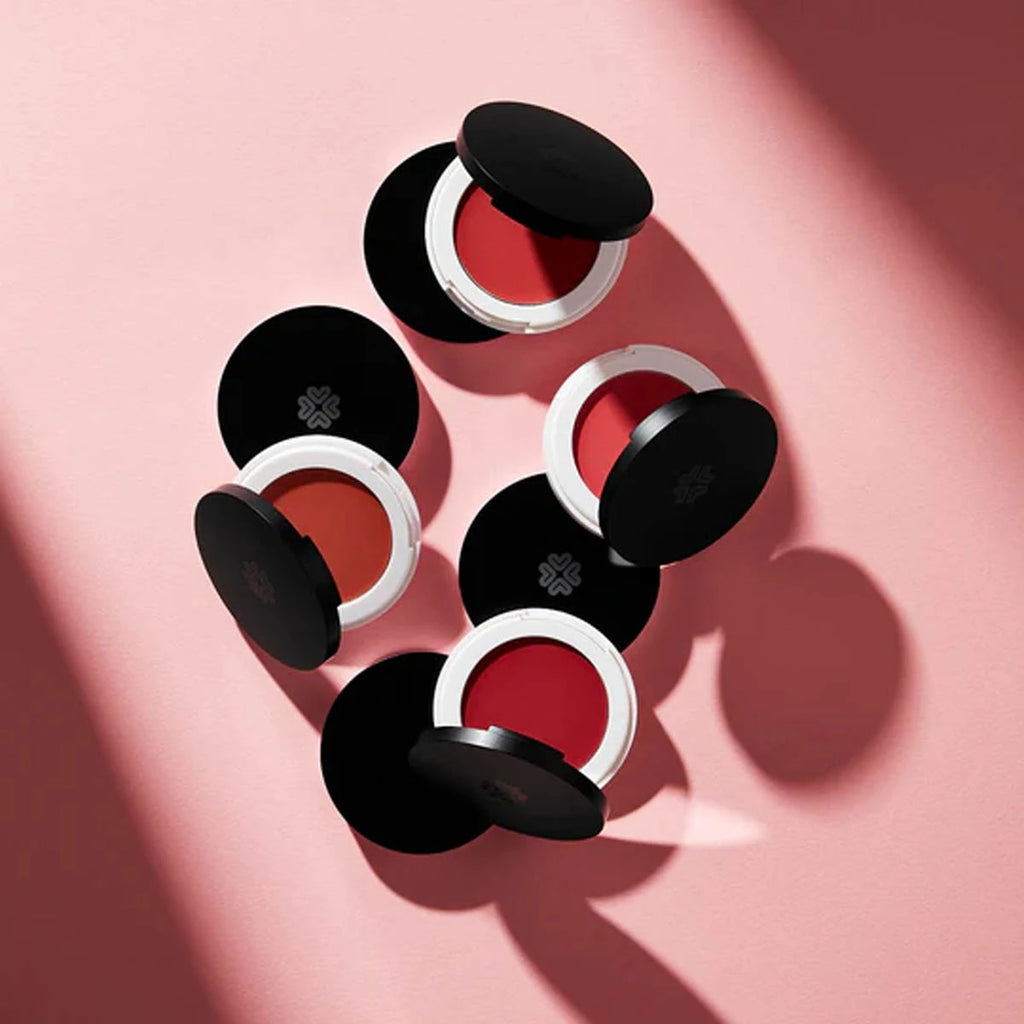 Compact makeup cases with red contents on a pink background