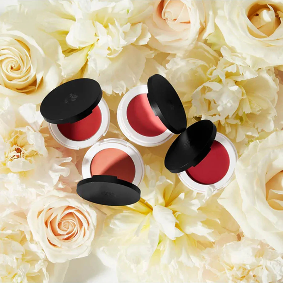 4 Lily Lolo Lip & Cheek Cream compact shades on a bed of white roses