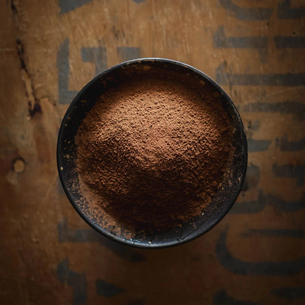 Cocoa powder in a black bowl on a cardboard background