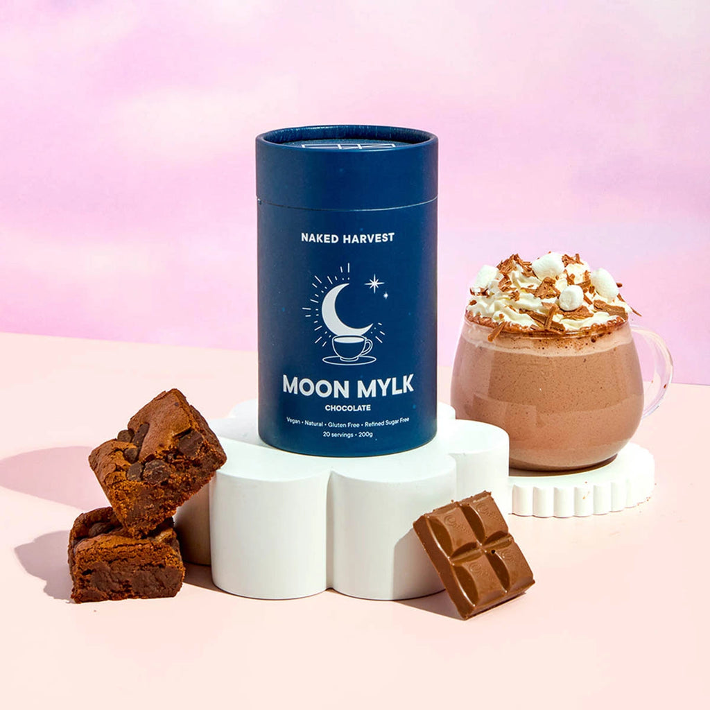 Naked Harvest Moon Mylk chocolate product with brownies and a hot chocolate mug on a pink background